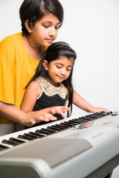 Carino ragazze indiane che suonano il pianoforte o la tastiera, uno strumento musicale — Foto Stock