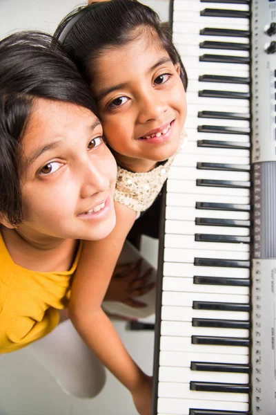 Carino ragazze indiane che suonano il pianoforte o la tastiera, uno strumento musicale — Foto Stock