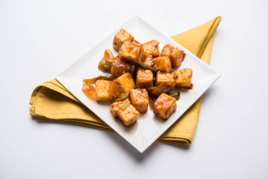 Baharatlı Paneer veya kuru biber paneer veya paneer tikka veya süzme peynir, kırmızı biber ve soğan, favori Hint başlangıç menüsü, seçici odak ile beyaz yemek servis