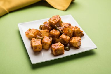 Baharatlı Paneer veya kuru biber paneer veya paneer tikka veya süzme peynir, kırmızı biber ve soğan, favori Hint başlangıç menüsü, seçici odak ile beyaz yemek servis