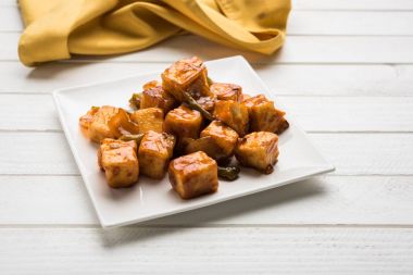 Baharatlı Paneer veya kuru biber paneer veya paneer tikka veya süzme peynir, kırmızı biber ve soğan, favori Hint başlangıç menüsü, seçici odak ile beyaz yemek servis