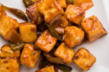 Baharatlı Paneer veya kuru biber paneer veya paneer tikka veya süzme peynir, kırmızı biber ve soğan, favori Hint başlangıç menüsü, seçici odak ile beyaz yemek servis