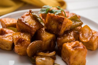 Baharatlı Paneer veya kuru biber paneer veya paneer tikka veya süzme peynir, kırmızı biber ve soğan, favori Hint başlangıç menüsü, seçici odak ile beyaz yemek servis