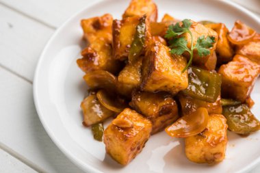 Baharatlı Paneer veya kuru biber paneer veya paneer tikka veya süzme peynir, kırmızı biber ve soğan, favori Hint başlangıç menüsü, seçici odak ile beyaz yemek servis