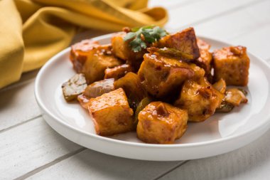 Baharatlı Paneer veya kuru biber paneer veya paneer tikka veya süzme peynir, kırmızı biber ve soğan, favori Hint başlangıç menüsü, seçici odak ile beyaz yemek servis