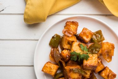 Baharatlı Paneer veya kuru biber paneer veya paneer tikka veya süzme peynir, kırmızı biber ve soğan, favori Hint başlangıç menüsü, seçici odak ile beyaz yemek servis