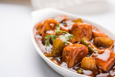 Baharatlı Paneer veya kuru biber paneer veya paneer tikka veya süzme peynir, kırmızı biber ve soğan, favori Hint başlangıç menüsü, seçici odak ile beyaz yemek servis