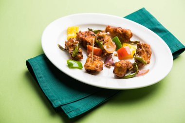 Baharatlı Paneer veya kuru biber paneer veya paneer tikka veya süzme peynir, kırmızı biber ve soğan, favori Hint başlangıç menüsü, seçici odak ile beyaz yemek servis