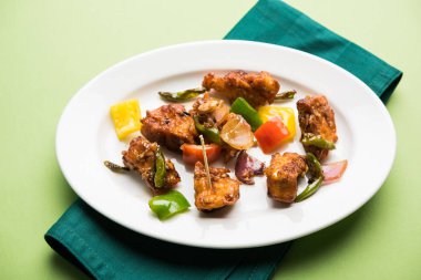 Baharatlı Paneer veya kuru biber paneer veya paneer tikka veya süzme peynir, kırmızı biber ve soğan, favori Hint başlangıç menüsü, seçici odak ile beyaz yemek servis