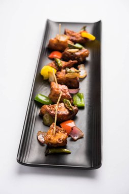 Baharatlı Paneer veya kuru biber paneer veya paneer tikka veya süzme peynir, kırmızı biber ve soğan, favori Hint başlangıç menüsü, seçici odak ile beyaz yemek servis