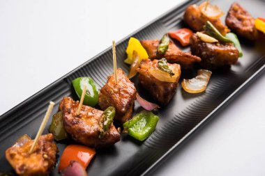 Baharatlı Paneer veya kuru biber paneer veya paneer tikka veya süzme peynir, kırmızı biber ve soğan, favori Hint başlangıç menüsü, seçici odak ile beyaz yemek servis