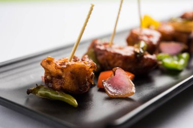 Baharatlı Paneer veya kuru biber paneer veya paneer tikka veya süzme peynir, kırmızı biber ve soğan, favori Hint başlangıç menüsü, seçici odak ile beyaz yemek servis