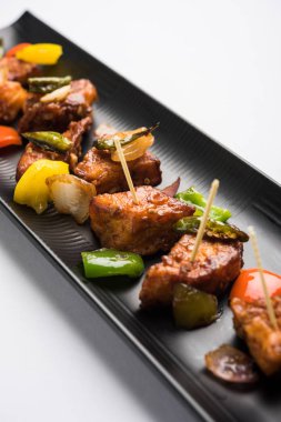 Baharatlı Paneer veya kuru biber paneer veya paneer tikka veya süzme peynir, kırmızı biber ve soğan, favori Hint başlangıç menüsü, seçici odak ile beyaz yemek servis