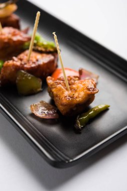 Baharatlı Paneer veya kuru biber paneer veya paneer tikka veya süzme peynir, kırmızı biber ve soğan, favori Hint başlangıç menüsü, seçici odak ile beyaz yemek servis