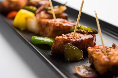 Baharatlı Paneer veya kuru biber paneer veya paneer tikka veya süzme peynir, kırmızı biber ve soğan, favori Hint başlangıç menüsü, seçici odak ile beyaz yemek servis