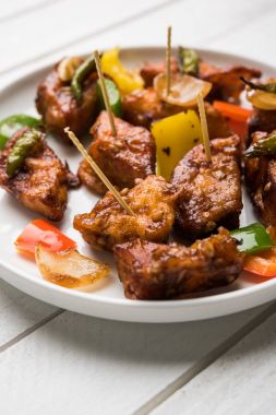 Baharatlı Paneer veya kuru biber paneer veya paneer tikka veya süzme peynir, kırmızı biber ve soğan, favori Hint başlangıç menüsü, seçici odak ile beyaz yemek servis