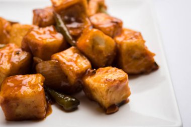 Baharatlı Paneer veya kuru biber paneer veya paneer tikka veya süzme peynir, kırmızı biber ve soğan, favori Hint başlangıç menüsü, seçici odak ile beyaz yemek servis
