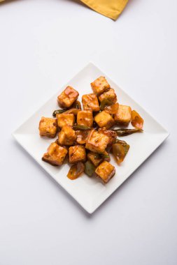 Baharatlı Paneer veya kuru biber paneer veya paneer tikka veya süzme peynir, kırmızı biber ve soğan, favori Hint başlangıç menüsü, seçici odak ile beyaz yemek servis