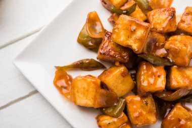 Baharatlı Paneer veya kuru biber paneer veya paneer tikka veya süzme peynir, kırmızı biber ve soğan, favori Hint başlangıç menüsü, seçici odak ile beyaz yemek servis