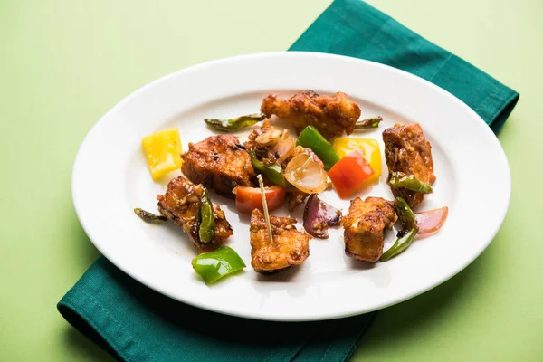 Baharatlı Paneer veya kuru biber paneer veya paneer tikka veya süzme peynir, kırmızı biber ve soğan, favori Hint başlangıç menüsü, seçici odak ile beyaz yemek servis