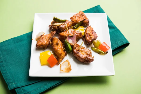 Baharatlı Paneer veya kuru biber paneer veya paneer tikka veya süzme peynir, kırmızı biber ve soğan, favori Hint başlangıç menüsü, seçici odak ile beyaz yemek servis