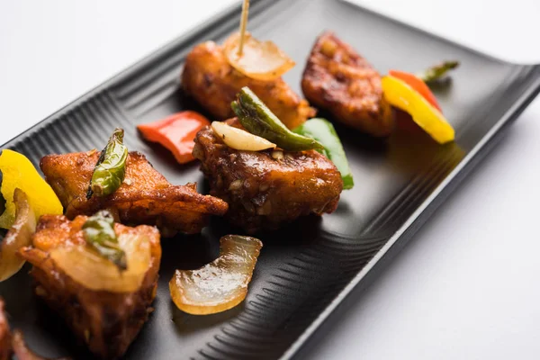 Baharatlı Paneer veya kuru biber paneer veya paneer tikka veya süzme peynir, kırmızı biber ve soğan, favori Hint başlangıç menüsü, seçici odak ile beyaz yemek servis