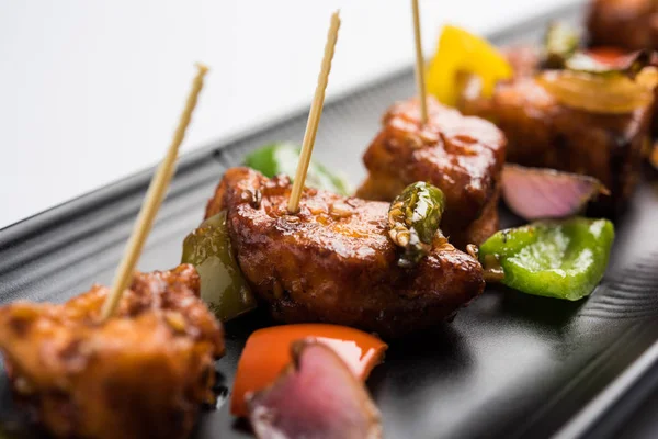 Baharatlı Paneer veya kuru biber paneer veya paneer tikka veya süzme peynir, kırmızı biber ve soğan, favori Hint başlangıç menüsü, seçici odak ile beyaz yemek servis