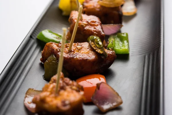 Baharatlı Paneer veya kuru biber paneer veya paneer tikka veya süzme peynir, kırmızı biber ve soğan, favori Hint başlangıç menüsü, seçici odak ile beyaz yemek servis