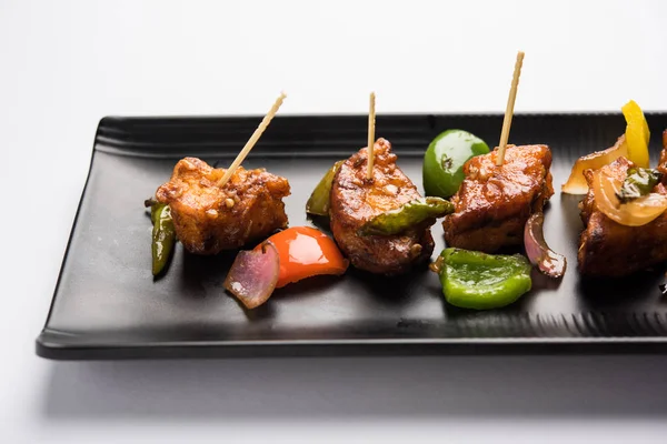 Baharatlı Paneer veya kuru biber paneer veya paneer tikka veya süzme peynir, kırmızı biber ve soğan, favori Hint başlangıç menüsü, seçici odak ile beyaz yemek servis