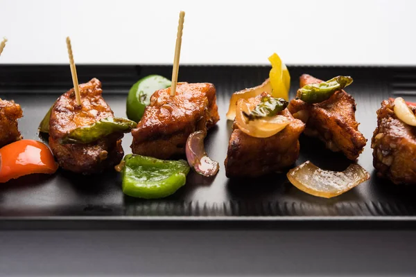 Baharatlı Paneer veya kuru biber paneer veya paneer tikka veya süzme peynir, kırmızı biber ve soğan, favori Hint başlangıç menüsü, seçici odak ile beyaz yemek servis