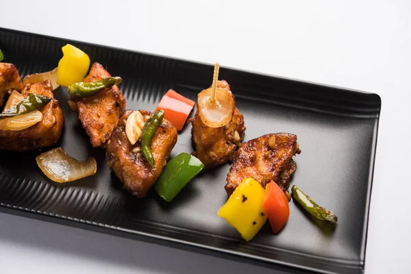 Baharatlı Paneer veya kuru biber paneer veya paneer tikka veya süzme peynir, kırmızı biber ve soğan, favori Hint başlangıç menüsü, seçici odak ile beyaz yemek servis