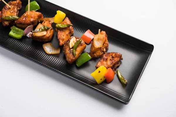 Baharatlı Paneer veya kuru biber paneer veya paneer tikka veya süzme peynir, kırmızı biber ve soğan, favori Hint başlangıç menüsü, seçici odak ile beyaz yemek servis