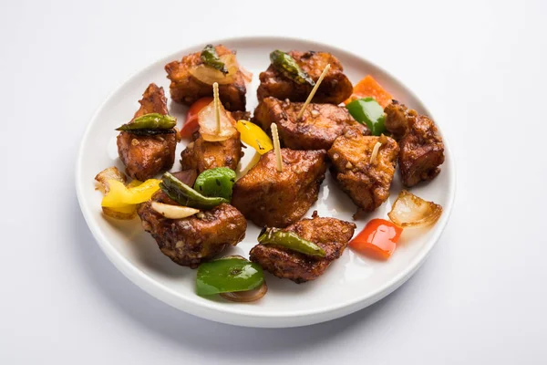 Baharatlı Paneer veya kuru biber paneer veya paneer tikka veya süzme peynir, kırmızı biber ve soğan, favori Hint başlangıç menüsü, seçici odak ile beyaz yemek servis