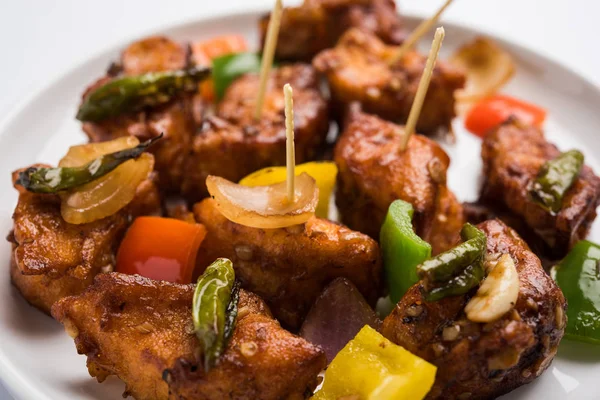 Baharatlı Paneer veya kuru biber paneer veya paneer tikka veya süzme peynir, kırmızı biber ve soğan, favori Hint başlangıç menüsü, seçici odak ile beyaz yemek servis