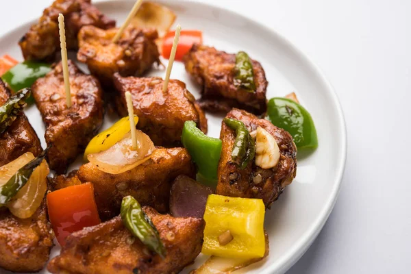 Baharatlı Paneer veya kuru biber paneer veya paneer tikka veya süzme peynir, kırmızı biber ve soğan, favori Hint başlangıç menüsü, seçici odak ile beyaz yemek servis