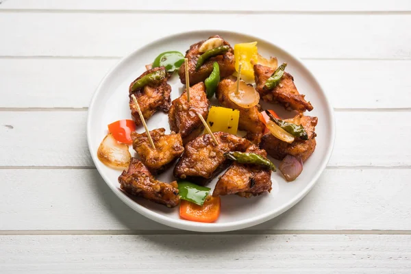 Baharatlı Paneer veya kuru biber paneer veya paneer tikka veya süzme peynir, kırmızı biber ve soğan, favori Hint başlangıç menüsü, seçici odak ile beyaz yemek servis