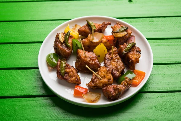 Baharatlı Paneer veya kuru biber paneer veya paneer tikka veya süzme peynir, kırmızı biber ve soğan, favori Hint başlangıç menüsü, seçici odak ile beyaz yemek servis