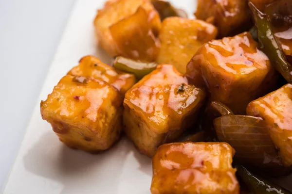 Baharatlı Paneer veya kuru biber paneer veya paneer tikka veya süzme peynir, kırmızı biber ve soğan, favori Hint başlangıç menüsü, seçici odak ile beyaz yemek servis
