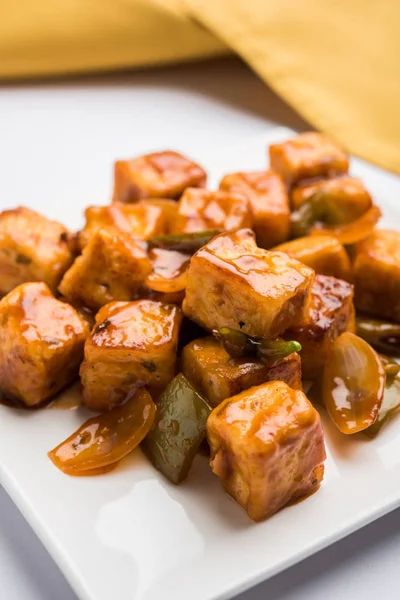 Baharatlı Paneer veya kuru biber paneer veya paneer tikka veya süzme peynir, kırmızı biber ve soğan, favori Hint başlangıç menüsü, seçici odak ile beyaz yemek servis
