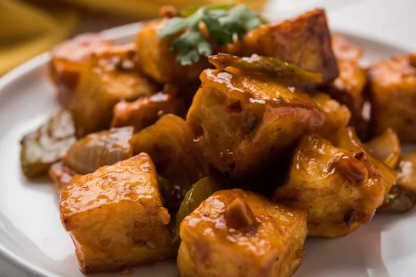 Baharatlı Paneer veya kuru biber paneer veya paneer tikka veya süzme peynir, kırmızı biber ve soğan, favori Hint başlangıç menüsü, seçici odak ile beyaz yemek servis