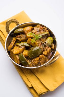 Hint baingan veya baigan ve aalu sabzi / Aloo Baingan tarifi / Hint baharatlı patlıcan ve patates köri, kadhai veya beyaz kase, seçici odak servis