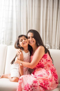 sevimli kızı mutlu Hintli anne ve kızı koltukta otururken birlikte portre sarılma Hintli akıllı anne