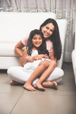 Bir Hint güzel küçük kız ya da annenin kucağına anne onu sıkıca ile her iki silah, seçici odak tutarak iken katta oturan kızın portresi