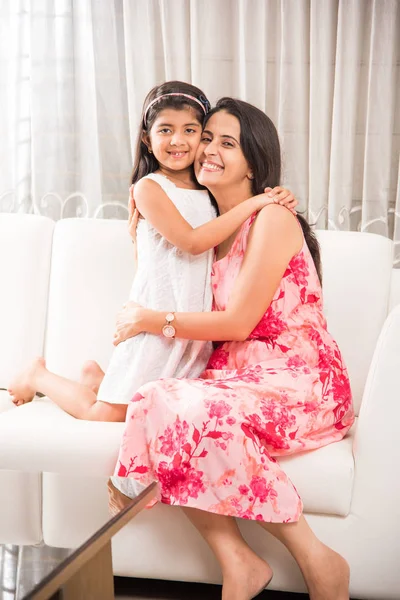 Indiano intelligente madre abbracciare il suo carino figlia, ritratto di felice indiano madre e figlia insieme mentre seduto su divano — Foto Stock