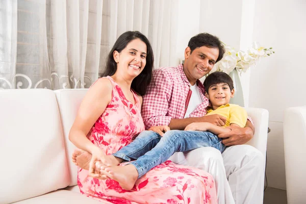 Candid Portrait of smart indian family of four while sitting on sofa. Indian or asian family group photo. Selective focus