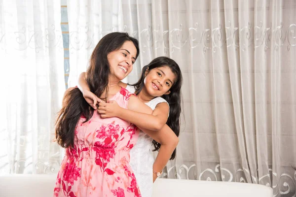 Indian smart mother hugging her cute daughter, Portrait of happy Indian mother and daughter together while sitting on sofa — Stock Photo, Image
