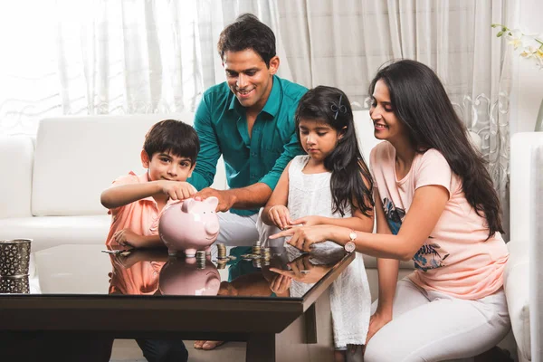 Mutlu genç Hintli çift evde çocuklarla kumbara tasarrufu önemi öğretme