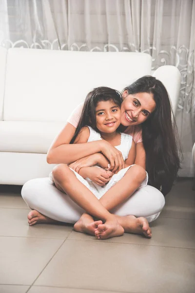 Porträtt av en indisk vacker liten flicka eller dotter sitter i mammas knä på golvet, medan mor håller henne tätt med båda armarna, selektivt fokus — Stockfoto