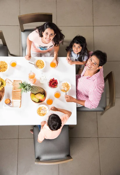 Top view of happy, smiling Asian Indian family of mother, father, son and daughter eating healthy food & salad at a dining table. Indians eating breakfast, lunch or dinner. Top view, Selective focus — Stock Photo, Image