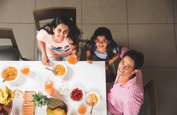 Vista superior de la feliz y sonriente familia india asiática de madre, padre, hijo e hija comiendo comida saludable y ensalada en una mesa de comedor. Indios desayunando, comiendo o cenando. Vista superior, enfoque selectivo —  Fotos de Stock